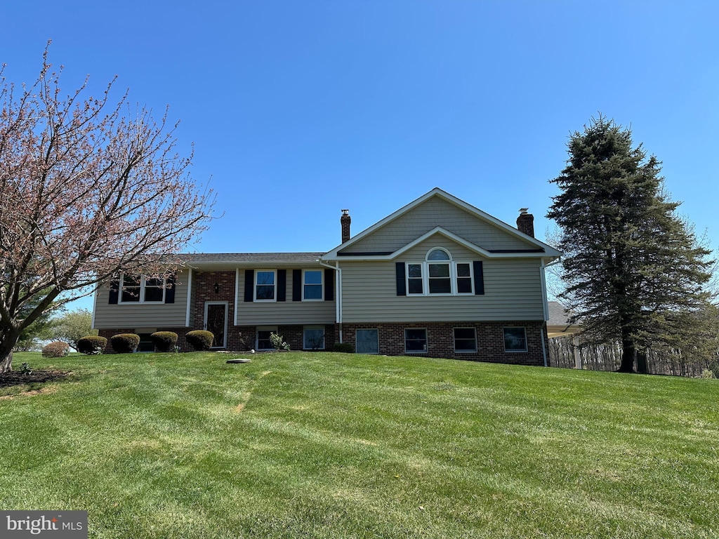 bi-level home featuring a front yard and a chimney