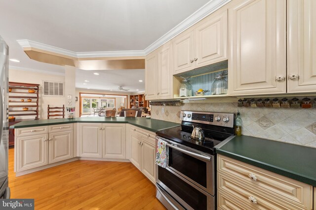 kitchen with dark countertops, decorative backsplash, stainless steel appliances, light wood finished floors, and a peninsula