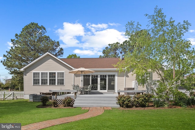 rear view of house with a lawn, fence, and a deck
