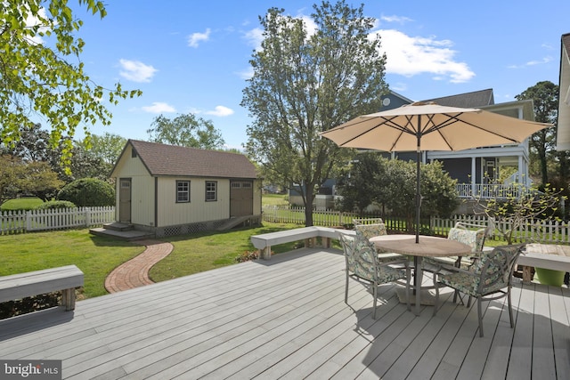 wooden deck featuring a lawn, an outbuilding, outdoor dining space, and fence private yard