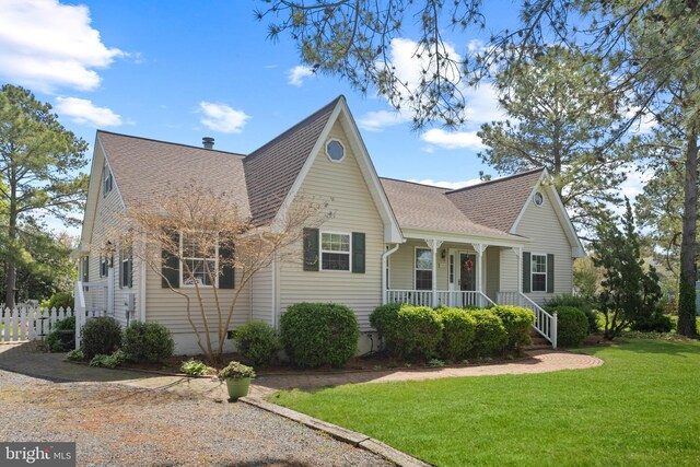 view of front facade featuring a shingled roof, a front yard, and covered porch