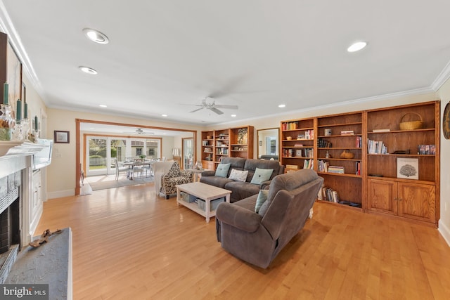 living room featuring recessed lighting, light wood-style floors, a premium fireplace, a ceiling fan, and crown molding