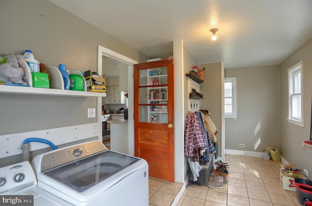 laundry area with light tile patterned flooring, baseboards, washer and dryer, and laundry area