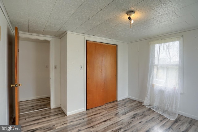 unfurnished bedroom featuring baseboards, a closet, and wood finished floors