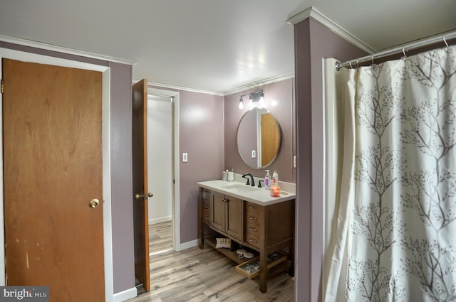 full bathroom featuring vanity, crown molding, baseboards, and wood finished floors