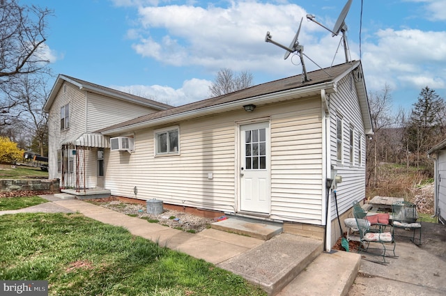 view of front of property featuring a wall mounted air conditioner and a front lawn