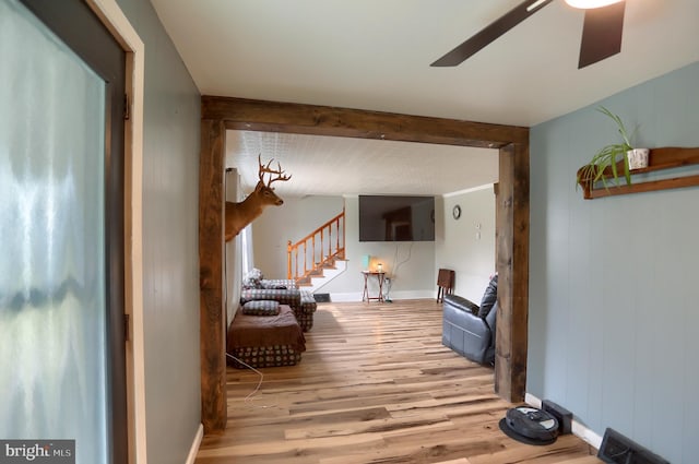 hall featuring beam ceiling, baseboards, stairs, and wood finished floors