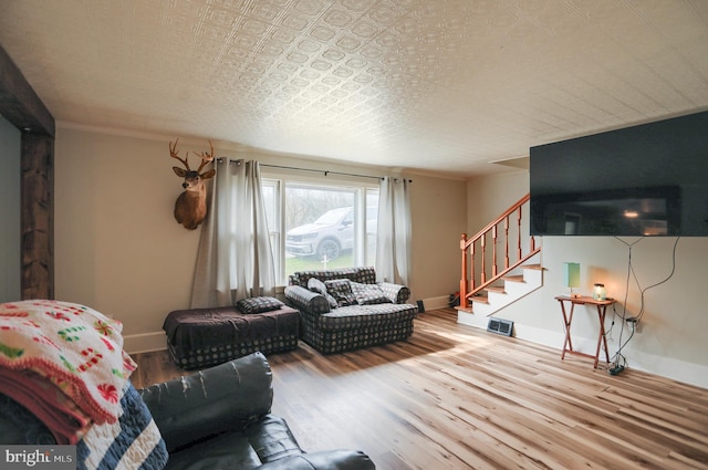 living room featuring baseboards, visible vents, wood finished floors, and stairway