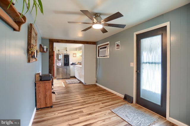 foyer entrance featuring baseboards, a wall mounted air conditioner, light wood finished floors, and ceiling fan