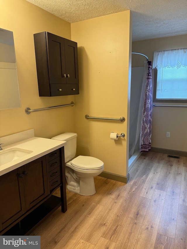 bathroom with toilet, a textured ceiling, a shower with shower curtain, and wood finished floors