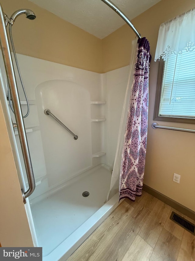 bathroom featuring baseboards, visible vents, a shower stall, and wood finished floors