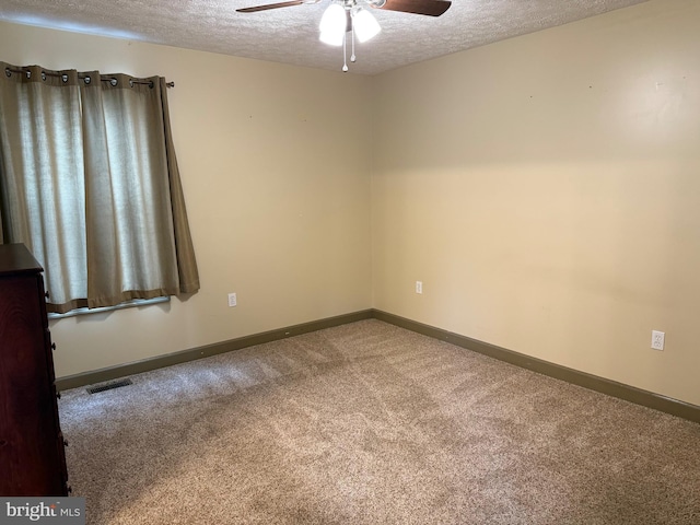 spare room with carpet flooring, a ceiling fan, a textured ceiling, baseboards, and visible vents