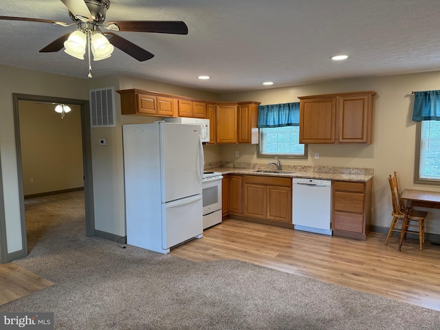 kitchen featuring a sink, brown cabinetry, white appliances, visible vents, and recessed lighting