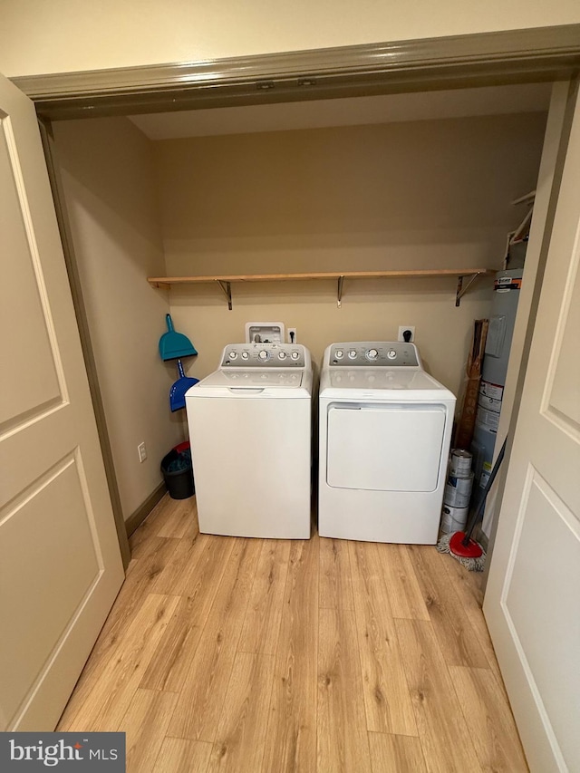 clothes washing area with light wood finished floors, independent washer and dryer, electric water heater, and laundry area