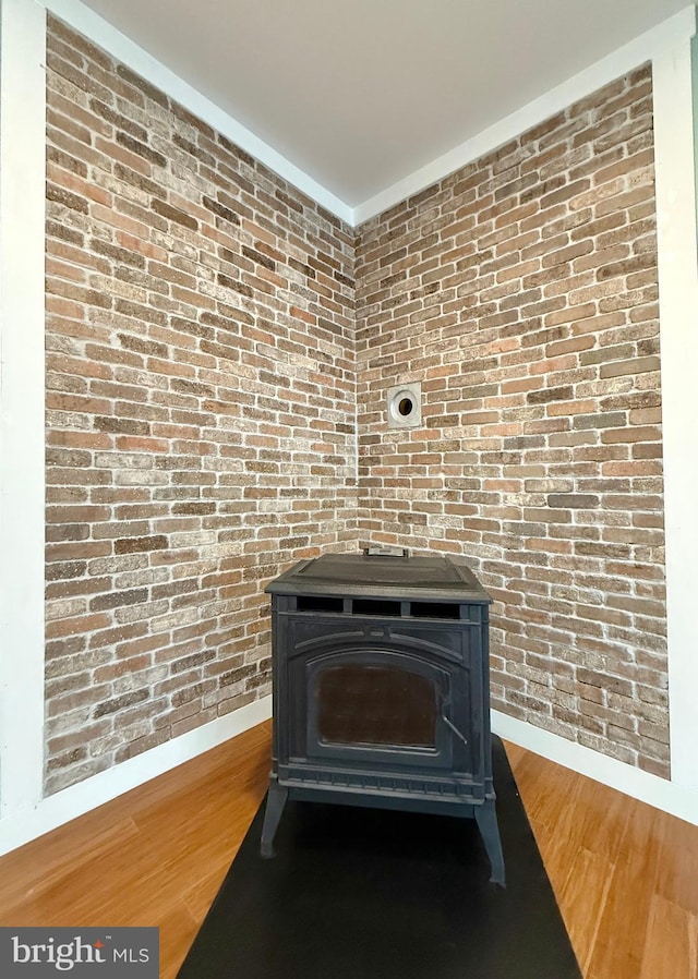 interior details featuring a wood stove, wood finished floors, and baseboards
