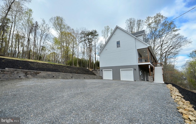 view of property exterior with gravel driveway, stairway, and an attached garage