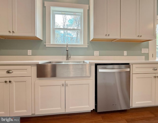 kitchen featuring stainless steel dishwasher, white cabinets, light countertops, and a sink