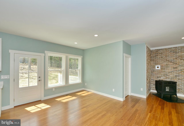 unfurnished living room with recessed lighting, a wood stove, light wood finished floors, and baseboards