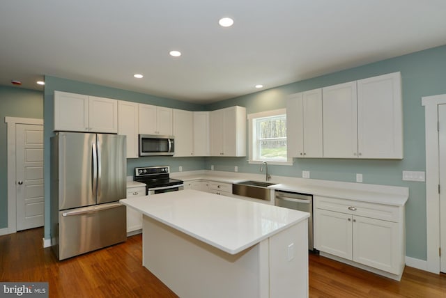 kitchen with a center island, a sink, dark wood-style flooring, white cabinetry, and stainless steel appliances