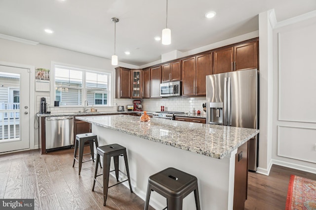 kitchen with wood finished floors, a kitchen breakfast bar, a sink, and appliances with stainless steel finishes