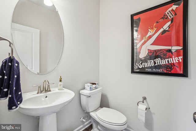 half bathroom featuring baseboards, a sink, and toilet