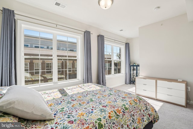 bedroom with visible vents, baseboards, and light carpet