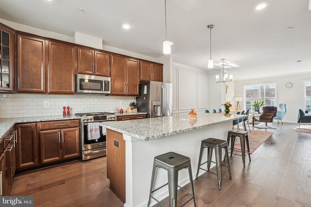 kitchen featuring appliances with stainless steel finishes, a notable chandelier, a breakfast bar area, and dark wood-style floors