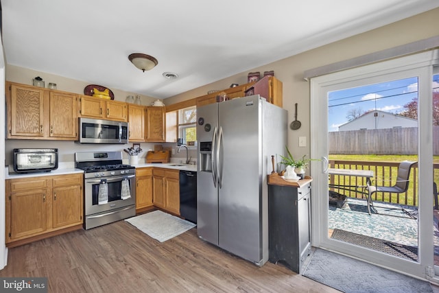 kitchen with visible vents, wood finished floors, light countertops, a sink, and stainless steel appliances
