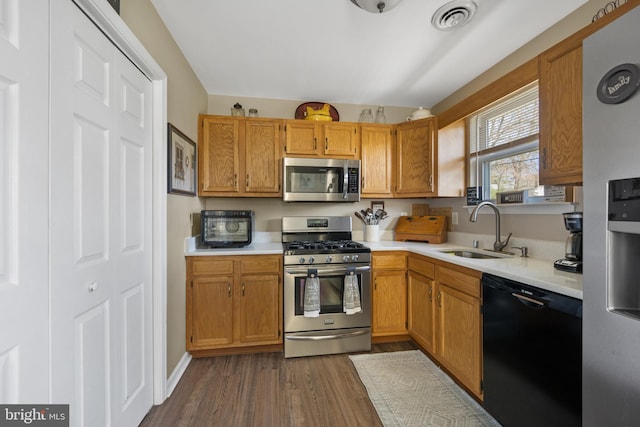kitchen featuring visible vents, a sink, light countertops, dark wood-style floors, and stainless steel appliances