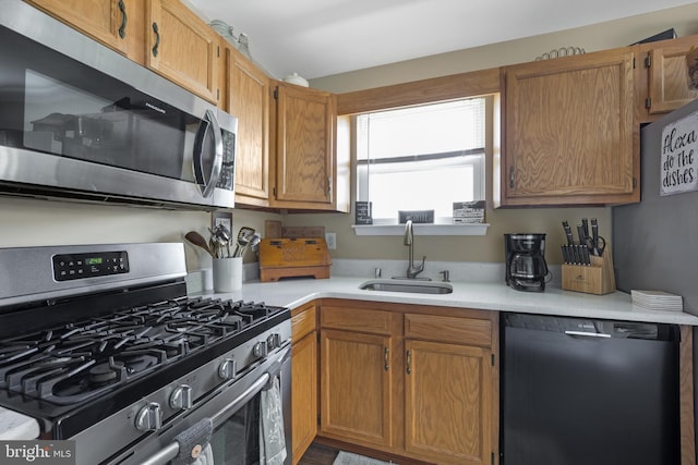 kitchen featuring light countertops, appliances with stainless steel finishes, a sink, and brown cabinetry