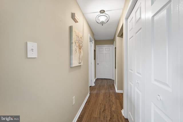 corridor featuring dark wood-type flooring and baseboards