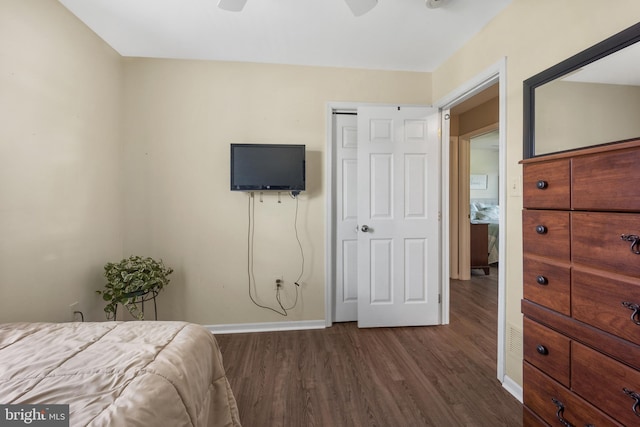 bedroom with a closet, dark wood-style flooring, baseboards, and a ceiling fan