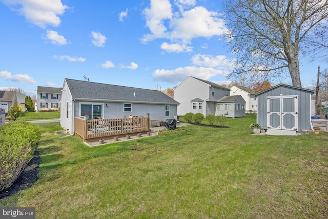 back of house with a yard, a deck, an outdoor structure, and a storage unit