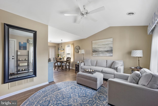 living area with baseboards, a ceiling fan, dark wood-type flooring, visible vents, and lofted ceiling