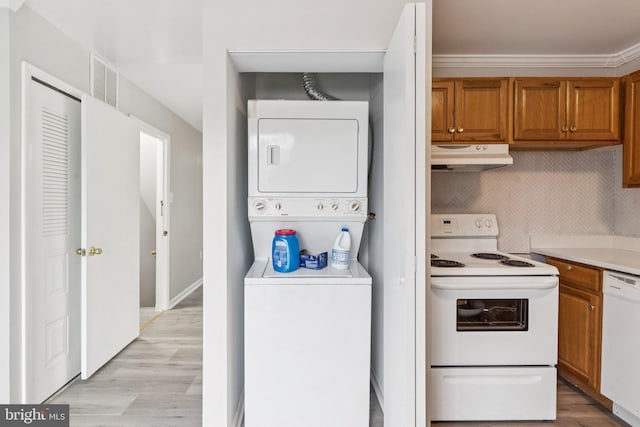 4647 6th St SE, Washington, DC 20032 - kitchen with white appliances, under cabinet range hood, stacked washer / dryer, brown cabinets, and light wood finished floors