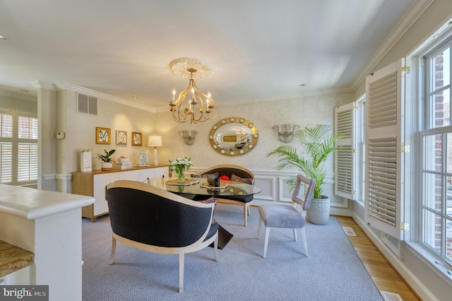 dining room with a wealth of natural light, ornamental molding, light wood-type flooring, and visible vents