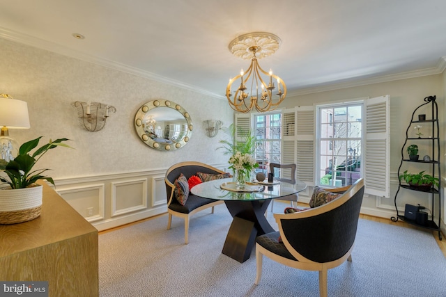 dining space featuring an inviting chandelier, a wainscoted wall, crown molding, and light carpet