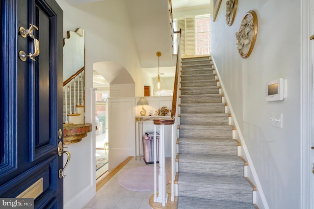 stairs featuring tile patterned flooring, arched walkways, and baseboards