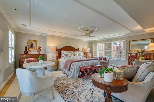 bedroom with crown molding, baseboards, light wood-type flooring, a tray ceiling, and visible vents
