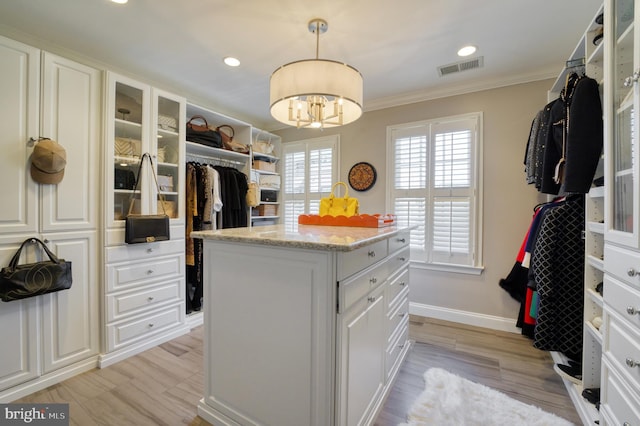 spacious closet featuring visible vents, light wood-style floors, and a notable chandelier