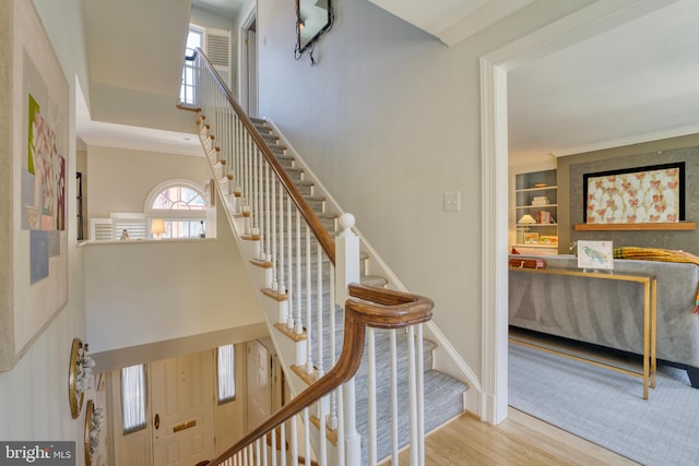 staircase with crown molding, baseboards, wood finished floors, and a towering ceiling