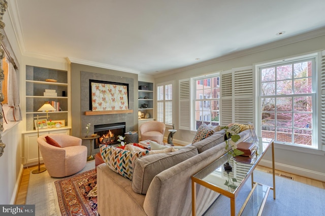 living room with crown molding, light wood-style floors, baseboards, and a tile fireplace
