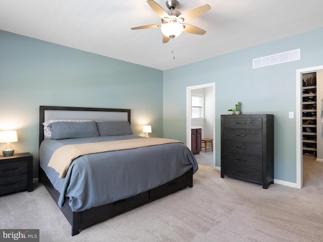 carpeted bedroom with baseboards, visible vents, a walk in closet, and ceiling fan