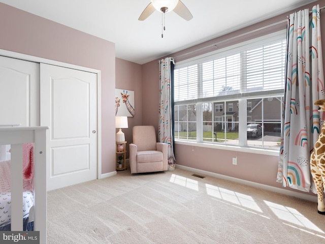 living area with carpet, visible vents, a ceiling fan, and baseboards