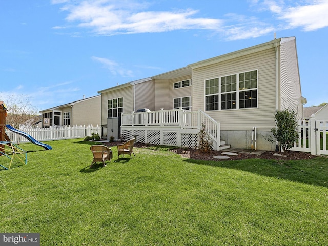 back of house featuring a yard, fence, a deck, and a playground