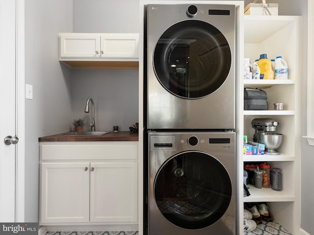 laundry area featuring stacked washer and clothes dryer, cabinet space, and a sink