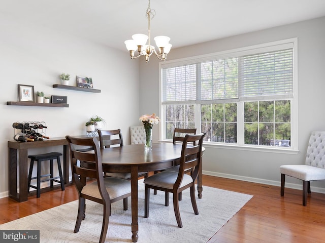 dining room featuring plenty of natural light, baseboards, wood finished floors, and an inviting chandelier