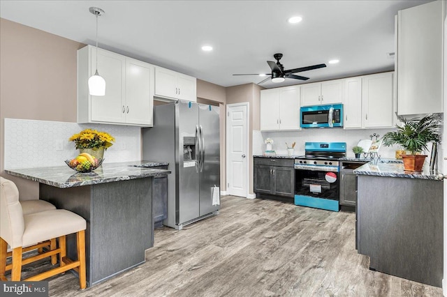 kitchen with a ceiling fan, stainless steel appliances, stone countertops, light wood finished floors, and white cabinets