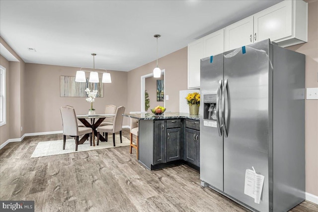 kitchen featuring white cabinets, stainless steel fridge, a peninsula, and light wood finished floors