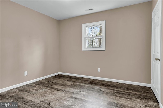 spare room featuring baseboards, dark wood-style flooring, and visible vents